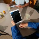 Hand houdt tablet beet op bruine eettafel
