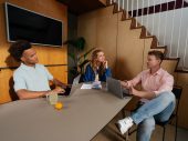 Drie zorgprofessionals die samen aan een tafel zitten te werken aan een project.
