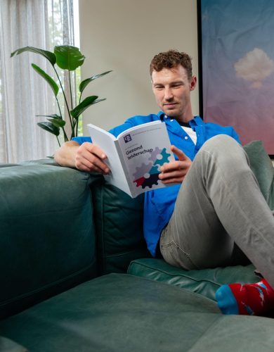Man leest boek zittend op bank