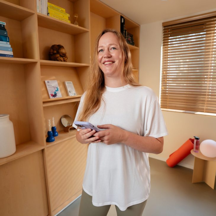 Lachende vrouw met telefoon in hand in yogastudio