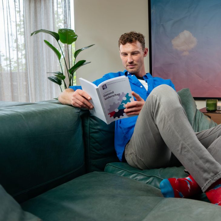 Man leest boek zittend op bank