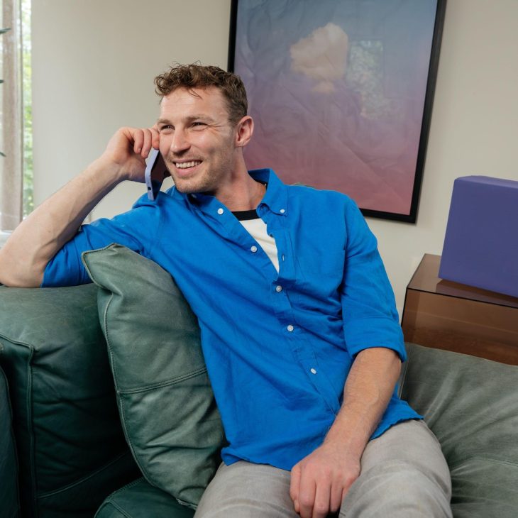 Man in blauw overhemd bellend op bank