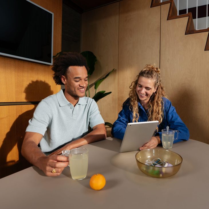Man en vrouw kijken samen naar tablet en drinken thee