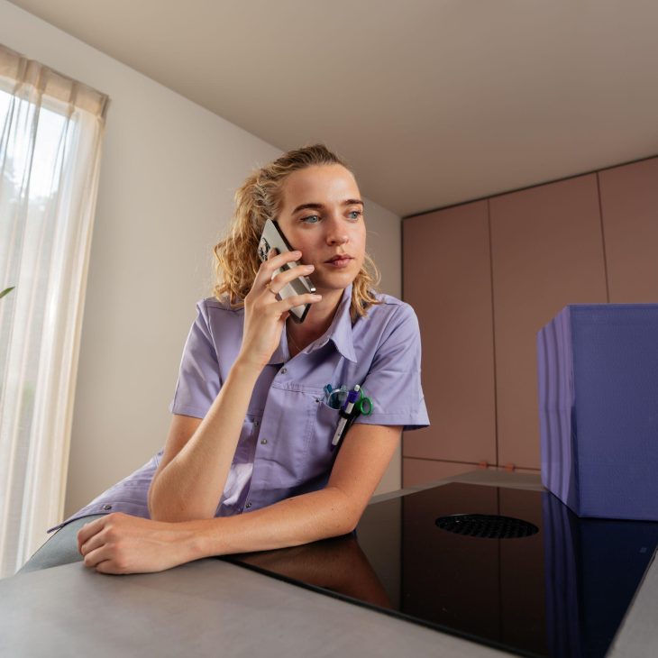 Vrouw in paars jasje heeft telefoon aan oor