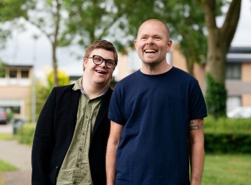 2 lachende mannen, man met bril heeft syndroom van Down