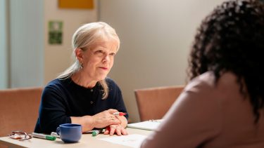 Blonde vrouw aan tafel, met pen in hand