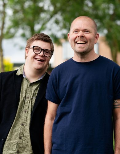 2 lachende mannen, man met bril heeft syndroom van Down