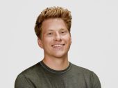 Portretfoto van een jonge man, kort haar en een donker shirt met lange mouwen voor een witte achtergrond