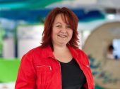 Vrouw met rood haar, zwart shirt en rode jas.