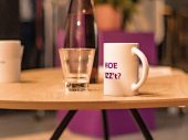 Glas en mok staan naast elkaar op een licht, houten tafeltje