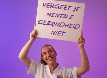 Vrouwelijke zorgmedewerker in wit uniform houdt bord omhoog met tekst 'Vergeet je mentale gezondheid niet' tegen paarse achtergrond