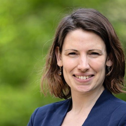 Gezicht van vrouw met middellang, bruin haar voor een groene, natuurlijke achtergrond