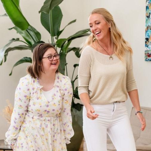 Rechts een vrouw met downsyndroom, rechts een lange, blonde vrouw met lichte kleding