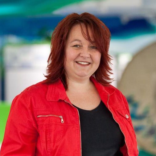 Vrouw met rood haar, zwart shirt en rode jas.