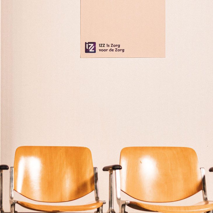 Twee lichte houten wachtkamerstoelen voor een lichte achtergrond