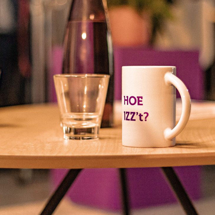 Glas en mok staan naast elkaar op een licht, houten tafeltje