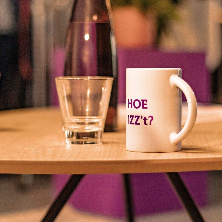 Glas en mok staan naast elkaar op een licht, houten tafeltje