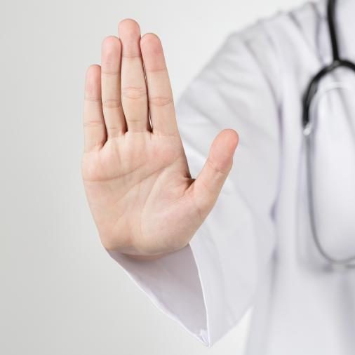 Persoon in wit uniform met stethoscoop steekt platte hand op