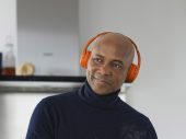Humberto Tan met een oranje koptelefoon haalt een theezakje uit een kop thee
