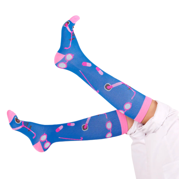 Twee benen in de lucht met donkerblauwe met roze zorgsokken aan, compressiesokken.