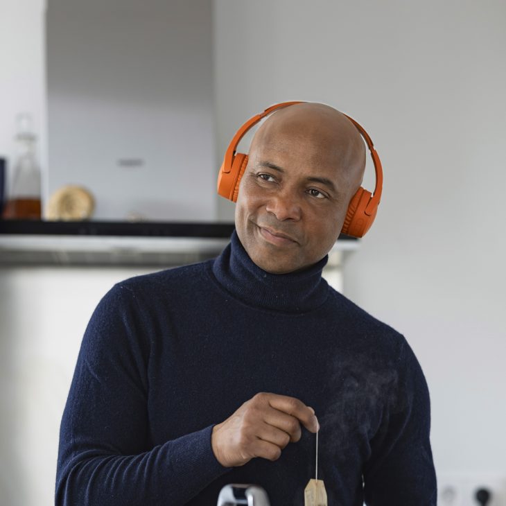 Humberto Tan met een oranje koptelefoon haalt een theezakje uit een kop thee