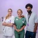 2 blonde vrouwen en een man met zwart haar. eerste vrouw draagt een witte verpleegkundige jas, tweede vrouw een operatiekamer outfit.