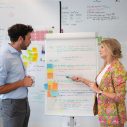 man en vrouw staan voor een flipover met teksten en post-its erop.