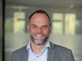 Portretfoto van Jan Luuk de Groot, een witte man met lichtblauw overhemd en grijs colbert