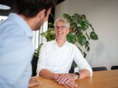 Foto van een man met bril en grijs haar met een wit overhemd