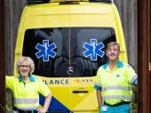 man en vrouw in ambulance outfit voor de achterkant van een ambulance