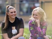 twee lachende vrouwen, een draagt een zwart tshirt met een beer