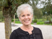 Portret van Marga Vrijmoeth, lachende vrouw met kort grijs haar en zwart shirt