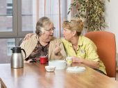 Twee vrouwen omarmen elkaar tijdens een koffiemoment