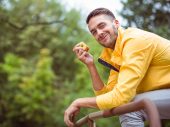 Man in gele jas eet appel en lacht naar camera