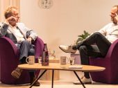 Twee mannen op paarse stoelen in gesprek met elkaar met een lage tafel ervoor