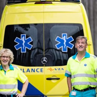 man en vrouw in ambulance outfit voor de achterkant van een ambulance