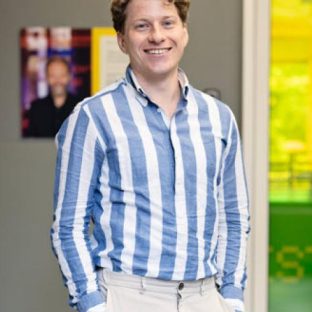 Man in blauw wit overhemd voor gele deur