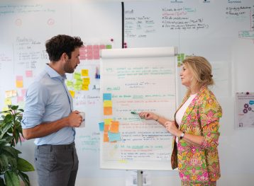 man en vrouw staan voor een flipover met teksten en post-its erop.