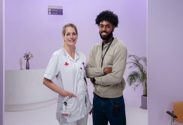 Man en vrouw met armen over elkaar voor paarse achtergrond.