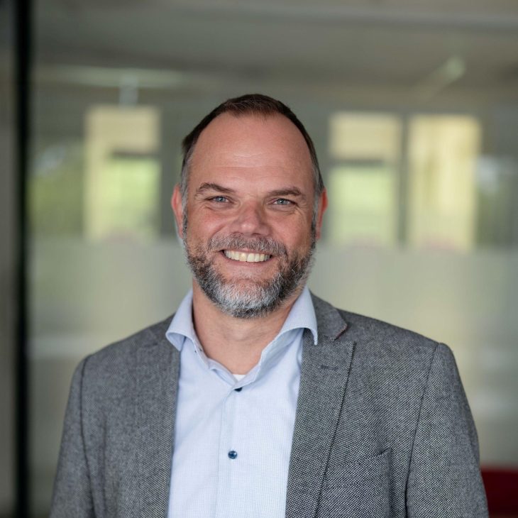 Portretfoto van Jan Luuk de Groot, een witte man met lichtblauw overhemd en grijs colbert