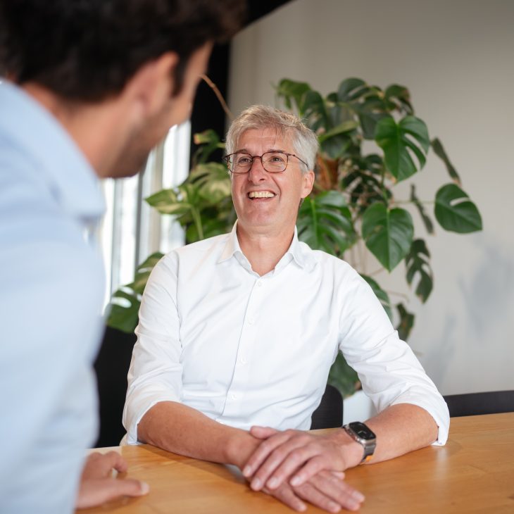 Foto van een man met bril en grijs haar met een wit overhemd