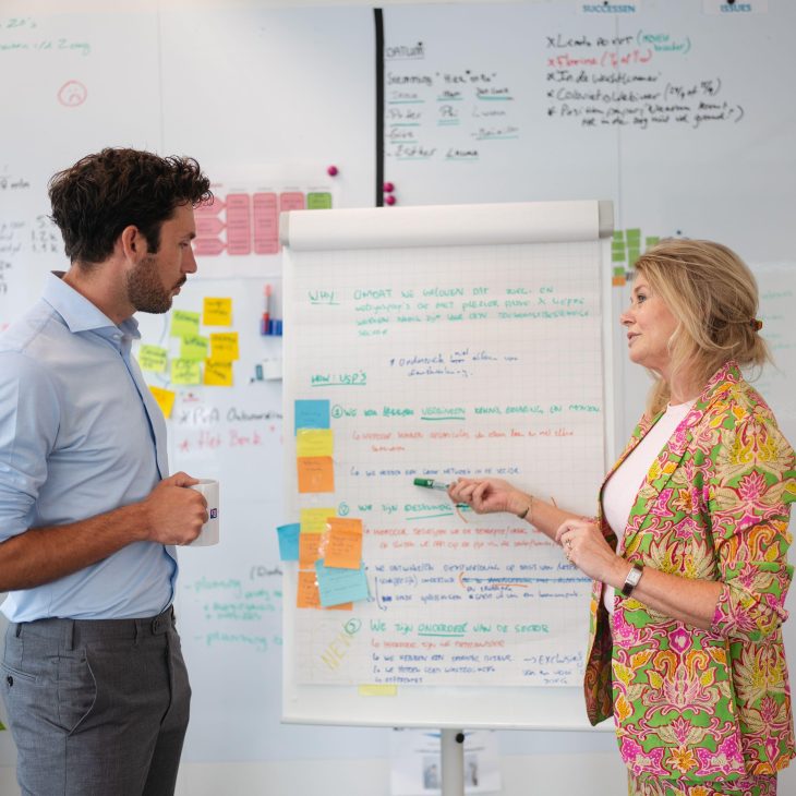 man en vrouw staan voor een flipover met teksten en post-its erop.