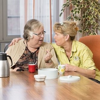 Twee vrouwen omarmen elkaar tijdens een koffiemoment