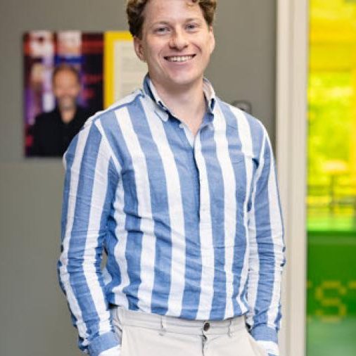 Man in blauw wit overhemd voor gele deur