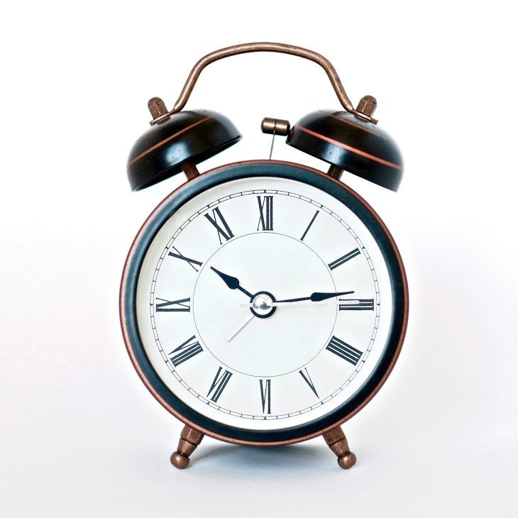 Zwarte wekker met witte wijzerplaat met Romeinse cijfers